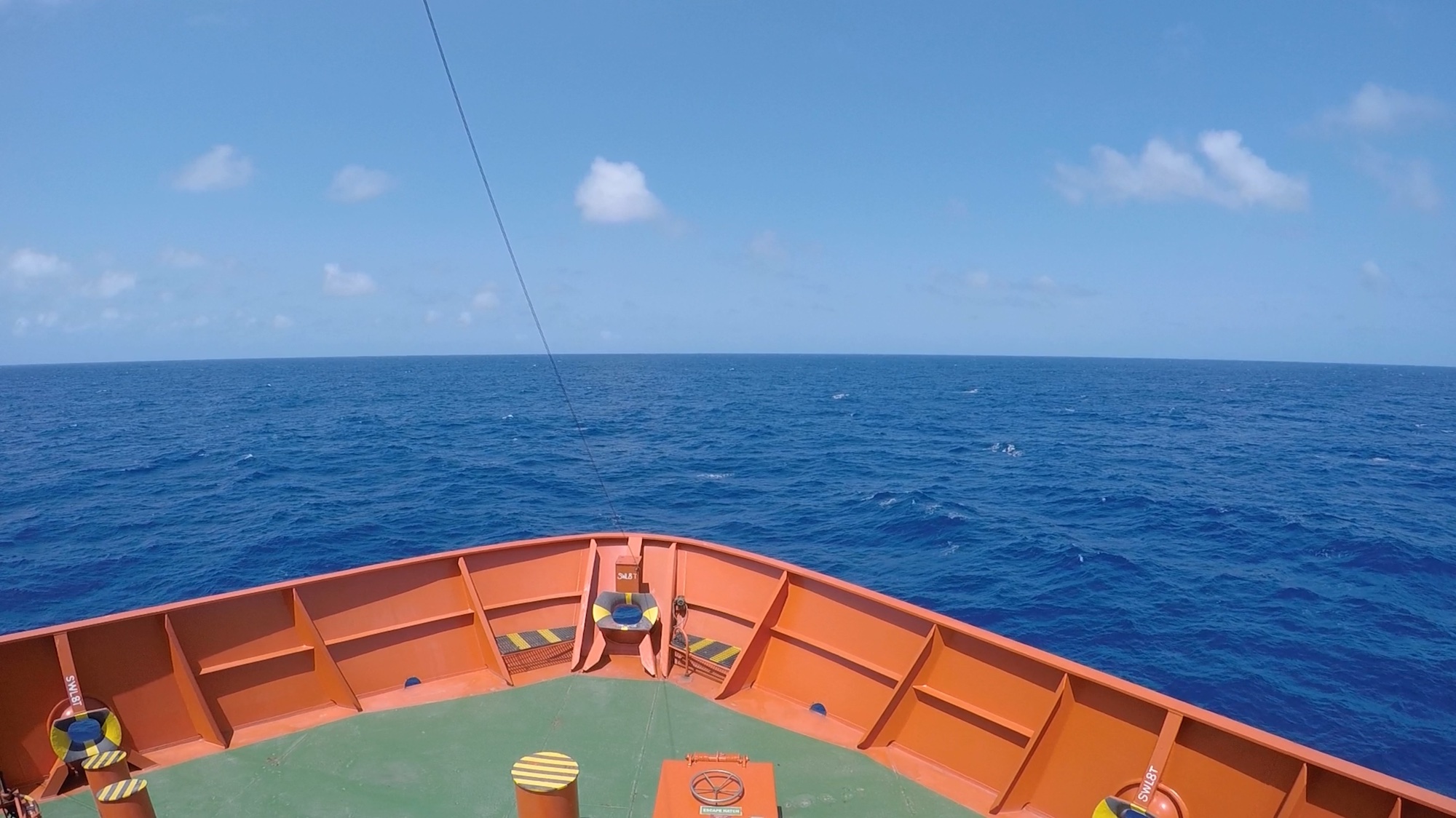 Looking down on an orange bow of a ship while cruising in bluewater